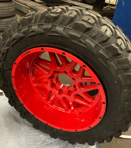Off-road truck wheel with red powder coat finish and mud tire